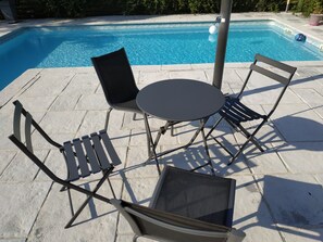 Ein Poolbereich mit Tisch und vier Stühlen sowie einer Zimmerpflanze.