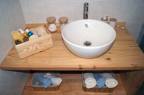 Ein Badezimmer mit einem Holzkonsolentisch, einem großen weißen Waschbecken und zwei Seifenspendern.