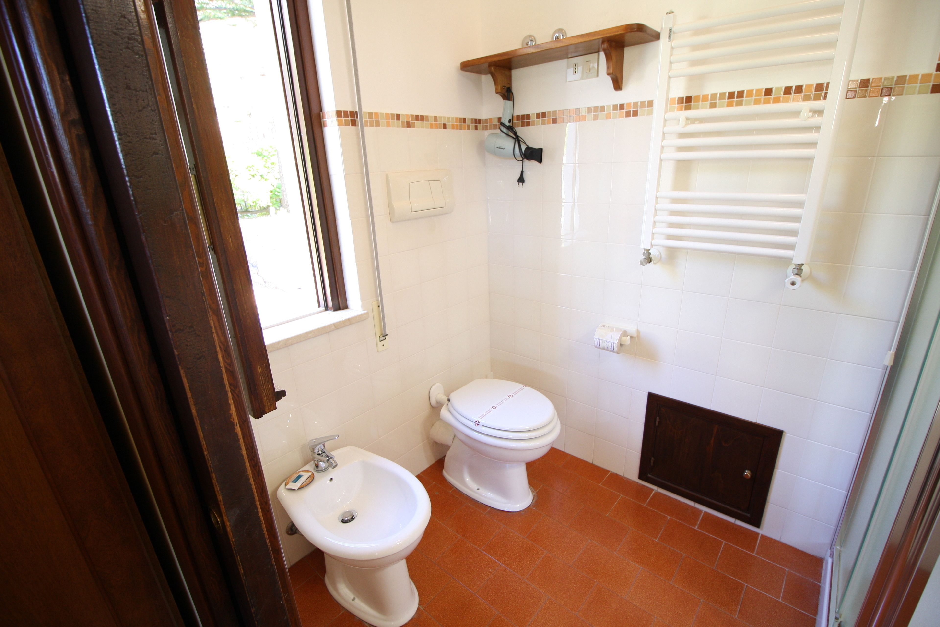Un baño con inodoro blanco, bidé, toallero y zona de ducha.