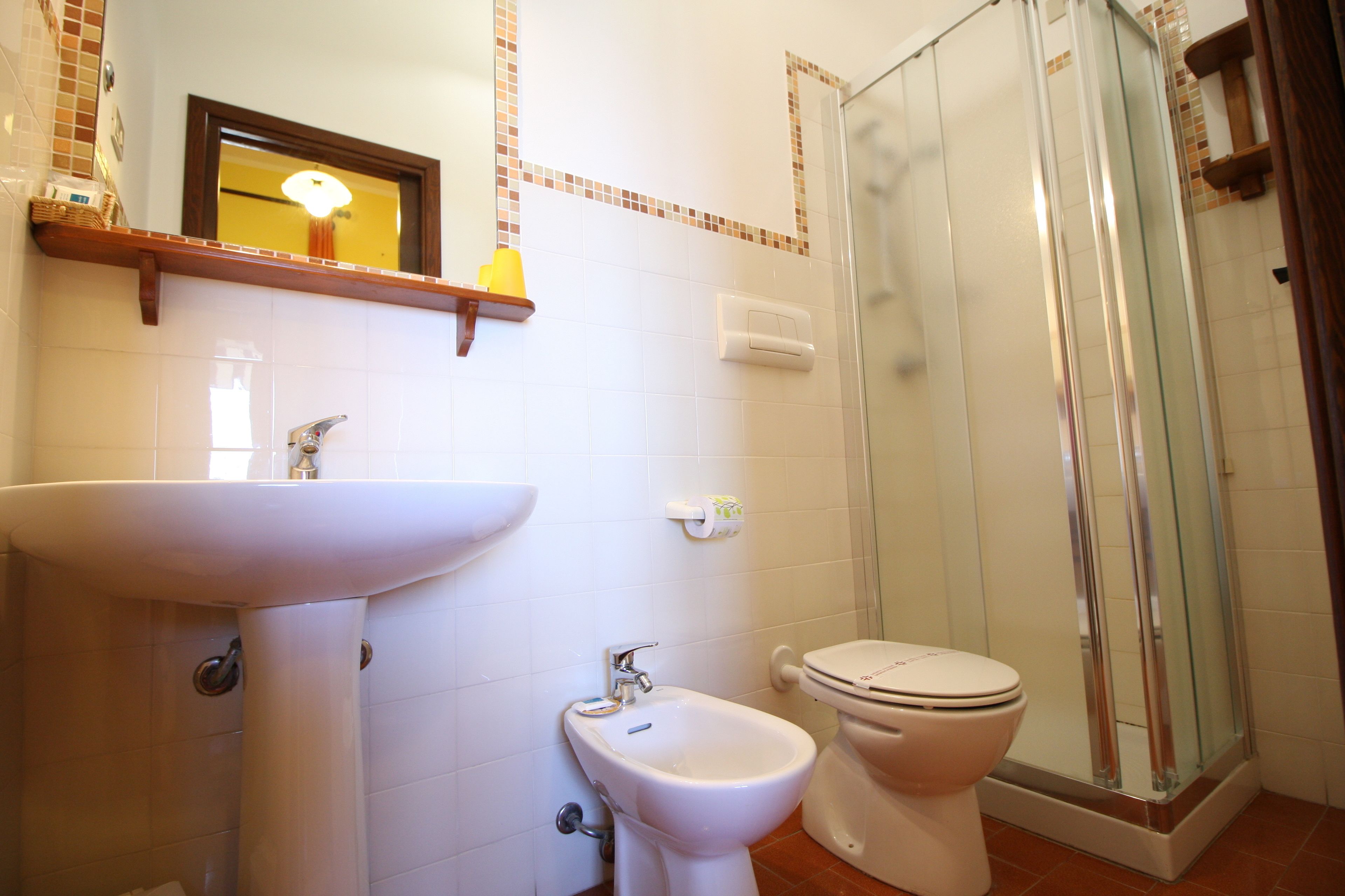 Un baño con lavamanos, bidé, inodoro y cabina de ducha de vidrio.