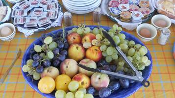 Una mesa con diferentes alimentos, incluyendo un plato azul con frutas, huevos y un cuchillo.