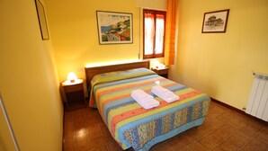 A hotel room with a bed, a nightstand, a lamp, and a window with curtains. - Bed & Breakfast Villa Rosa (Cefalù)