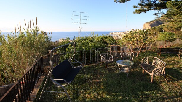 A patio with outdoor furniture, a metal fence, and a view of the sea. - Bed & Breakfast Villa Rosa (Cefalù)