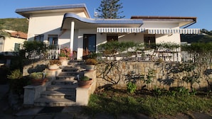 A modern two-story house with a stone staircase leading to the entrance, surrounded by potted plants and a stone wall. - Bed & Breakfast Villa Rosa (Cefalù)