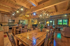 Um interior espaçoso em madeira, com uma grande mesa de jantar, assentos confortáveis, uma cozinha e uma sala de estar aconchegante.