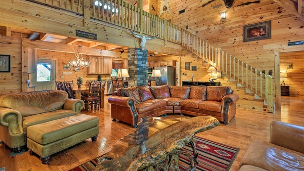 A spacious log cabin interior with a large wooden staircase, leather furniture, and a rustic decor including animal skulls and a fireplace. - Trenton Cabin w/ Hot Tub - 14 Mi to Lookout Mtn! (Trenton)
