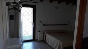 Een slaapkamer met een bed, nachtkastje, kledingkast en een raam met uitzicht.