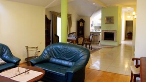 A spacious living room with leather sofas, a wooden coffee table, and a fireplace. - Klaipeda-Apartments (Klaipeda)