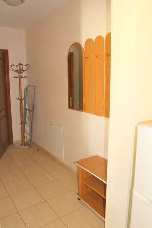 A hallway with a coat rack, a radiator, and a wooden shelf unit. - Klaipeda-Apartments (Klaipeda)