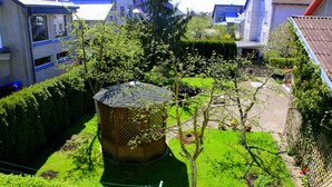 A garden with a wooden gazebo, neatly trimmed hedges, and a fenced area. - Klaipeda-Apartments (Klaipeda)