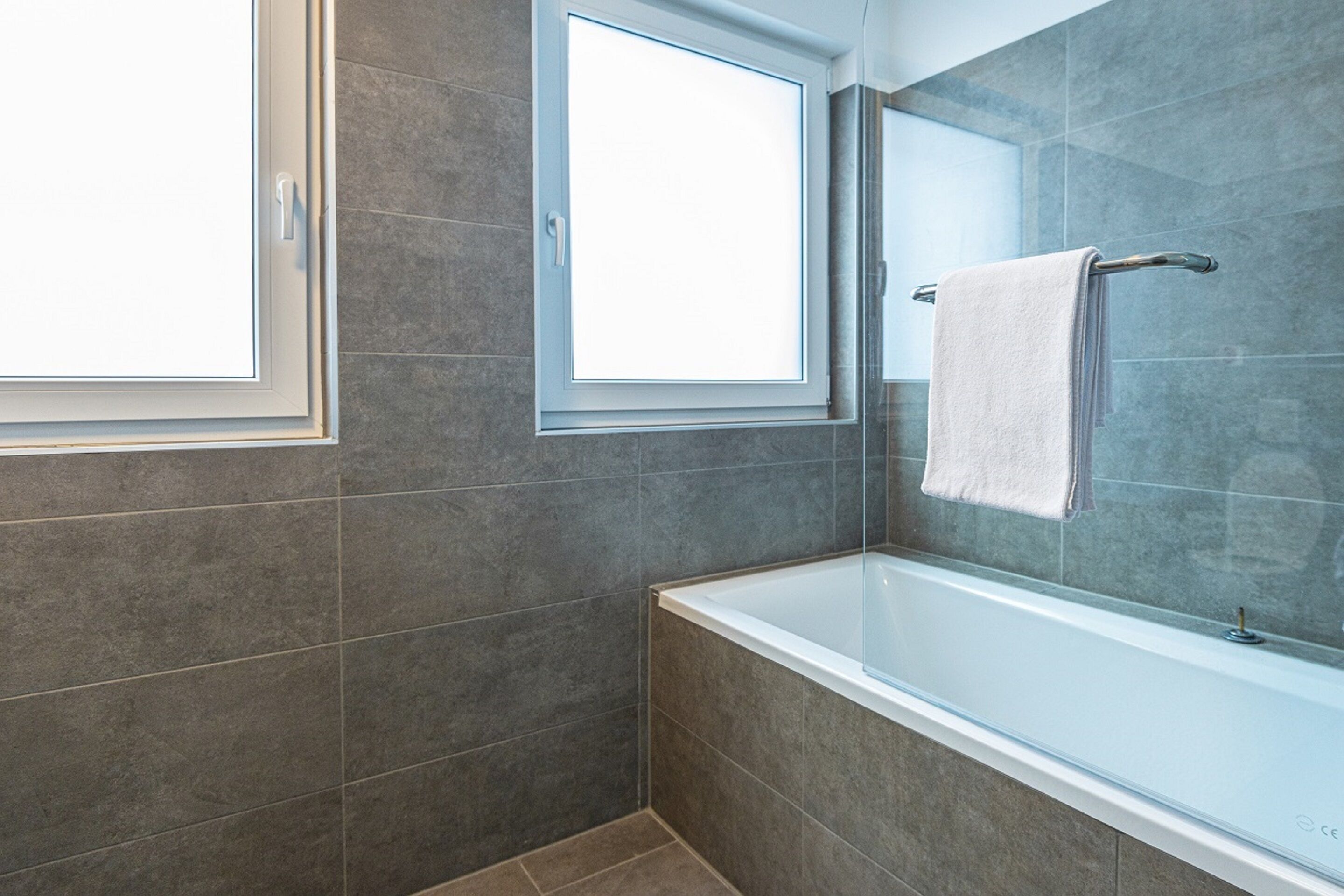Een moderne badkamer met een bad, een raam en een handdoekhouder.