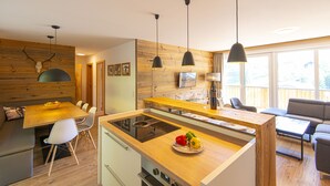 A modern kitchen with a central island, wooden accents, and pendant lighting. - Appartement Dorf Wagrain Alpenleben (Wagrain)
