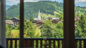 A view of a village with a church, houses, and a forested hill. - Appartement Dorf Wagrain Alpenleben (Wagrain)