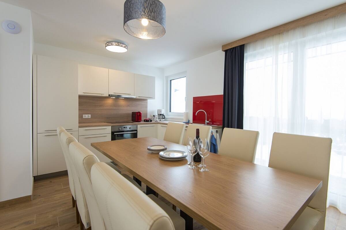 Een moderne keuken met witte kasten, een houten aanrecht en een eethoek met een houten tafel en witte stoelen.