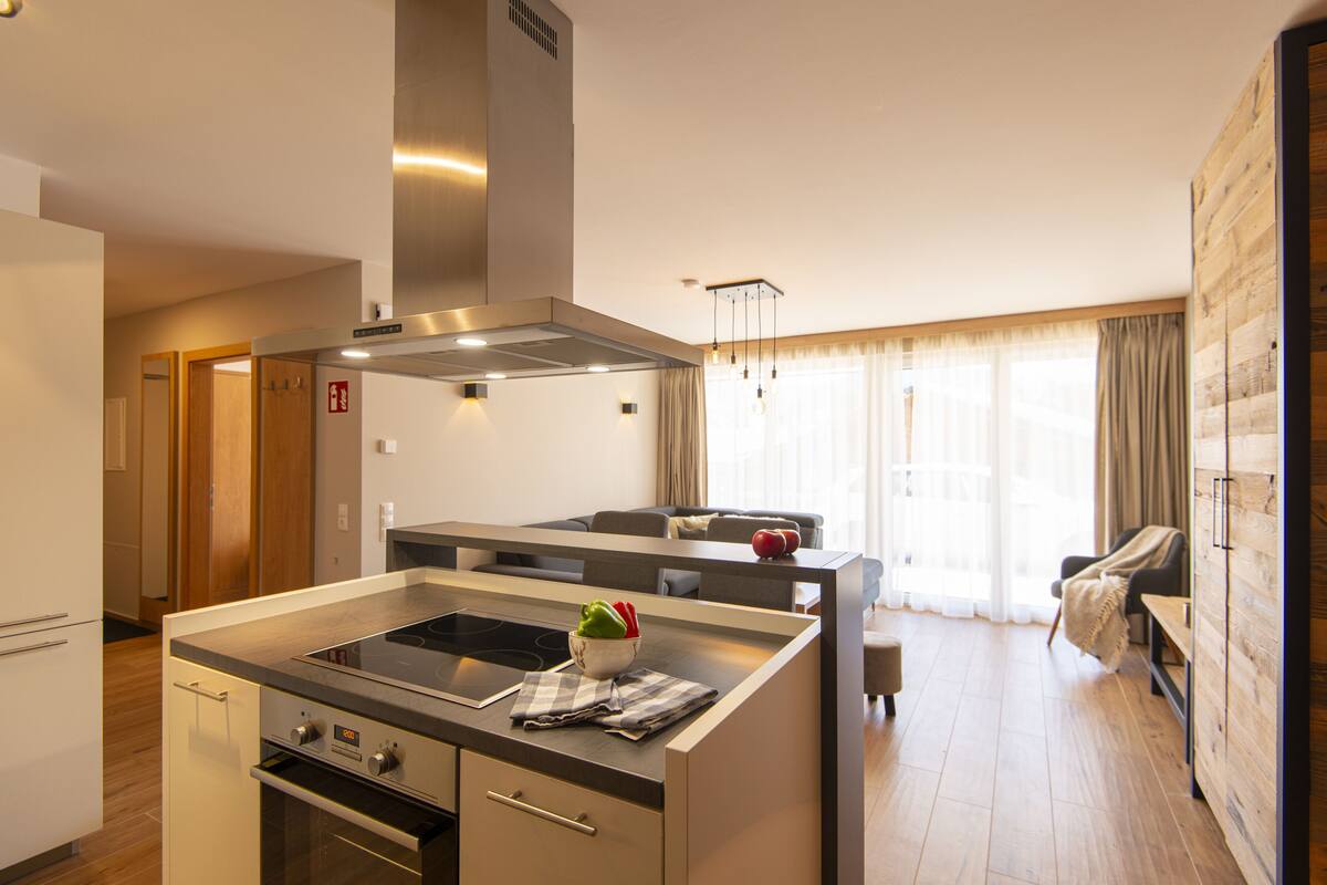Een moderne keuken met een centraal eiland, een inbouwoven en een roestvrijstalen afzuigkap.