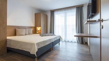 Un dormitorio moderno con una cama grande, armario de madera, lámpara de noche y televisor montado en la pared.