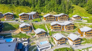 A cluster of multi-story buildings with balconies, arranged in a row with a pool area in the foreground. - Appartement Dorf Wagrain Alpenleben (Wagrain)