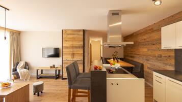Eine moderne Küche mit Holzelementen, ein Essbereich mit Tisch und Stühlen sowie ein an der Wand befestigter Fernseher.