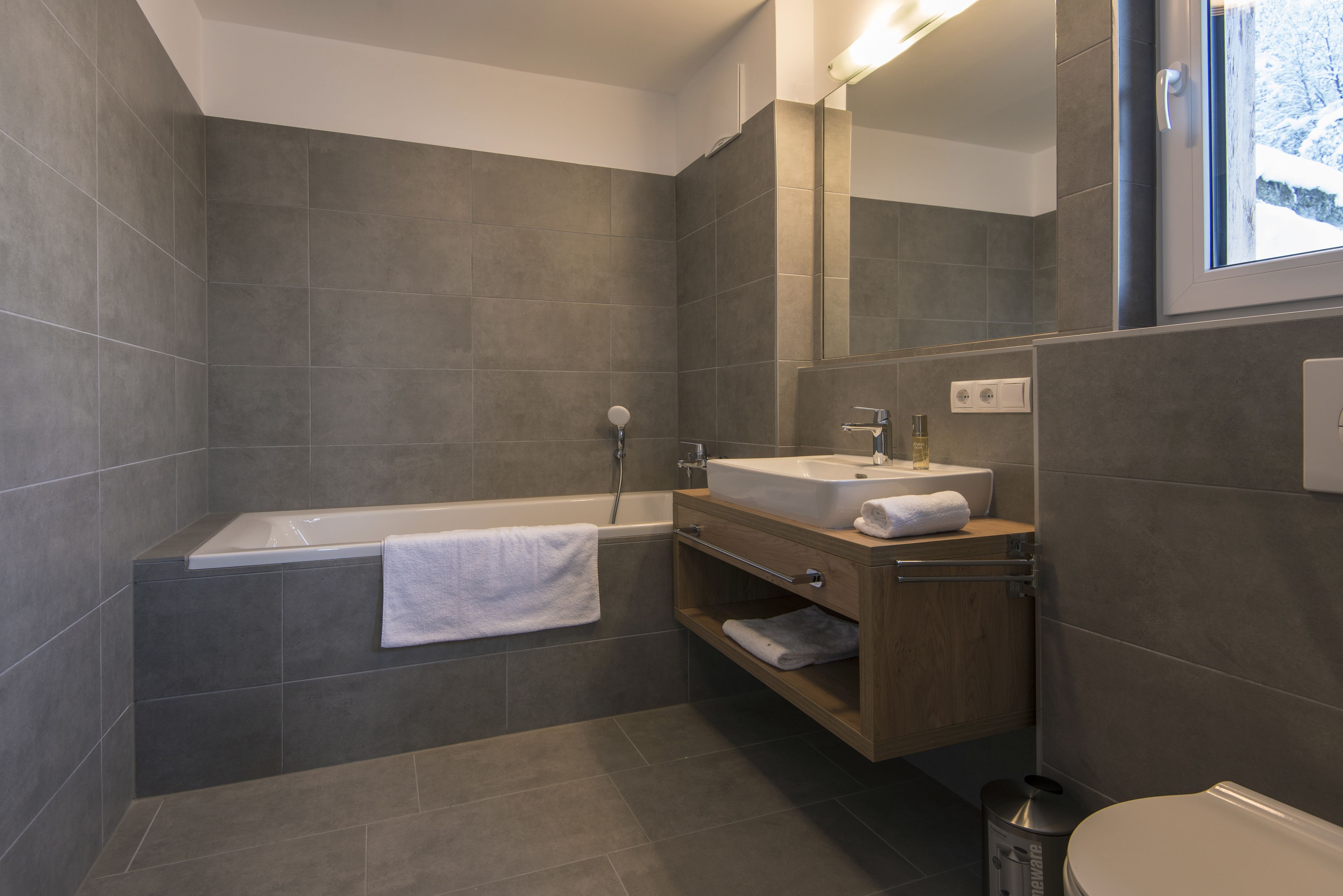 A modern bathroom with a bathtub, vanity, and toilet.