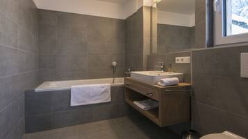A modern bathroom with a bathtub, vanity, and toilet.