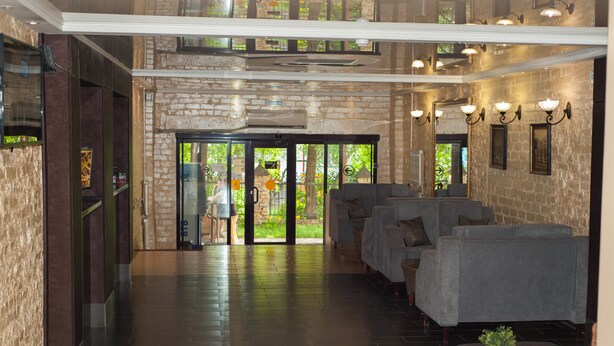 A hotel lobby with a stone wall, a reception desk, and a seating area with sofas.