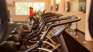 A row of stationary bikes in a gym with a person in the background.