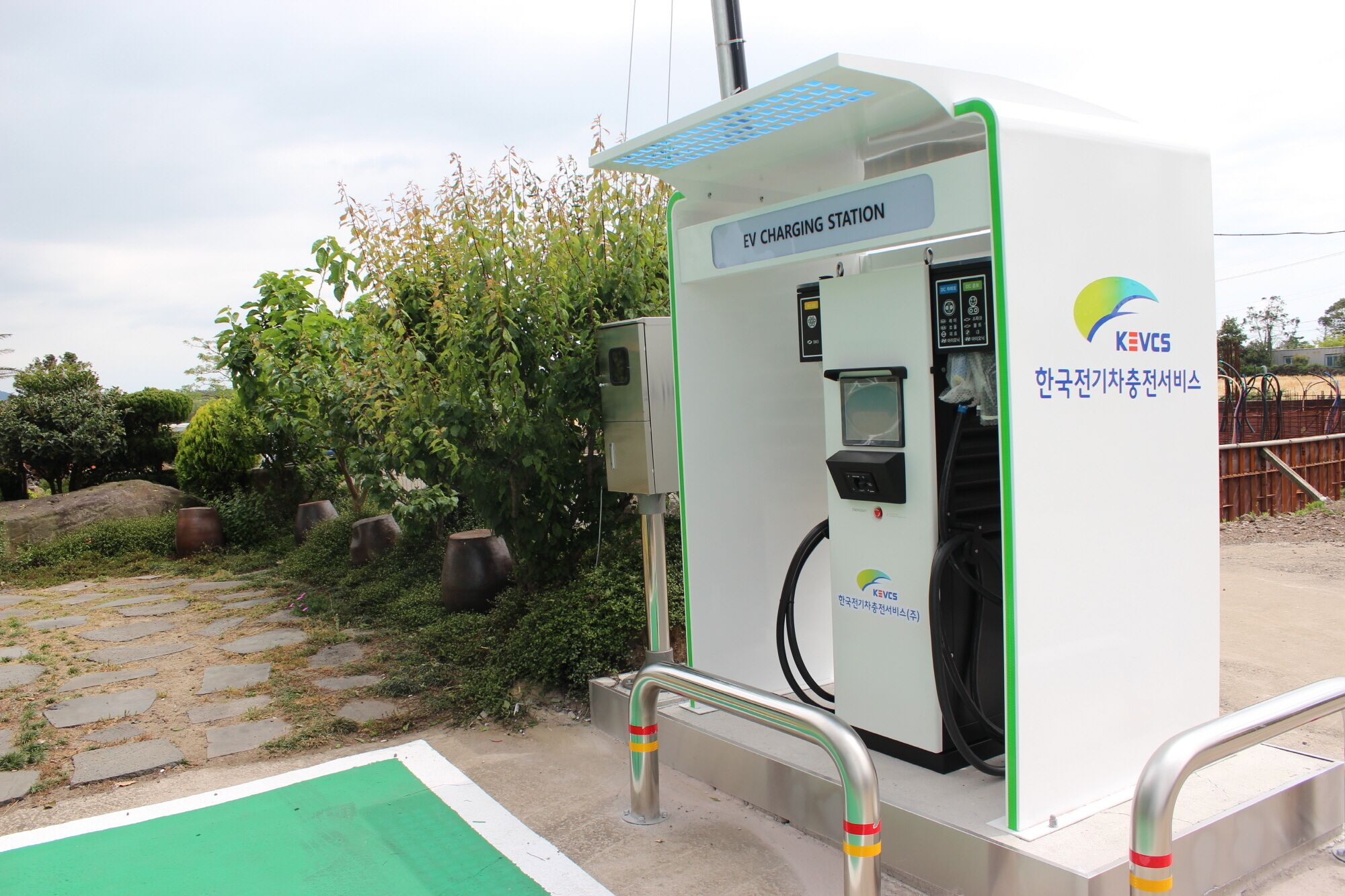 Een laadstation voor elektrische voertuigen met een digitaal scherm, een laadpoort en een veiligheidshek.