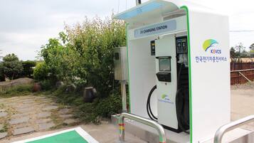 Een laadstation voor elektrische voertuigen met een digitaal scherm, een laadpoort en een veiligheidshek.