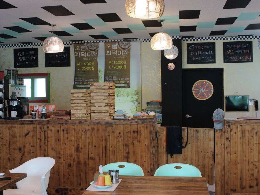 A restaurant interior with a checkered ceiling, wooden panel walls, and a counter displaying pizza boxes.
