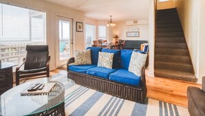 A living room with a wicker sofa, a glass coffee table, and a staircase. - Beach Front Home Seconds Away From The Beach (Freeport)