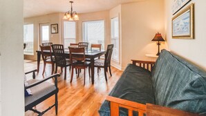 A dining area with a wooden table and chairs, a sofa, and a chandelier. - Beach Front Home Seconds Away From The Beach (Freeport)