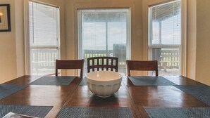 A dining area with a wooden table, four chairs, a central white bowl, and two pendant lights. - Beach Front Home Seconds Away From The Beach (Freeport)