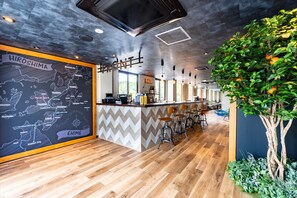 A modern bar area with a map of Hiroshima, bar stools, and a decorative tree. - I-Link Hostel & Cafe Shimanami (Imabari)