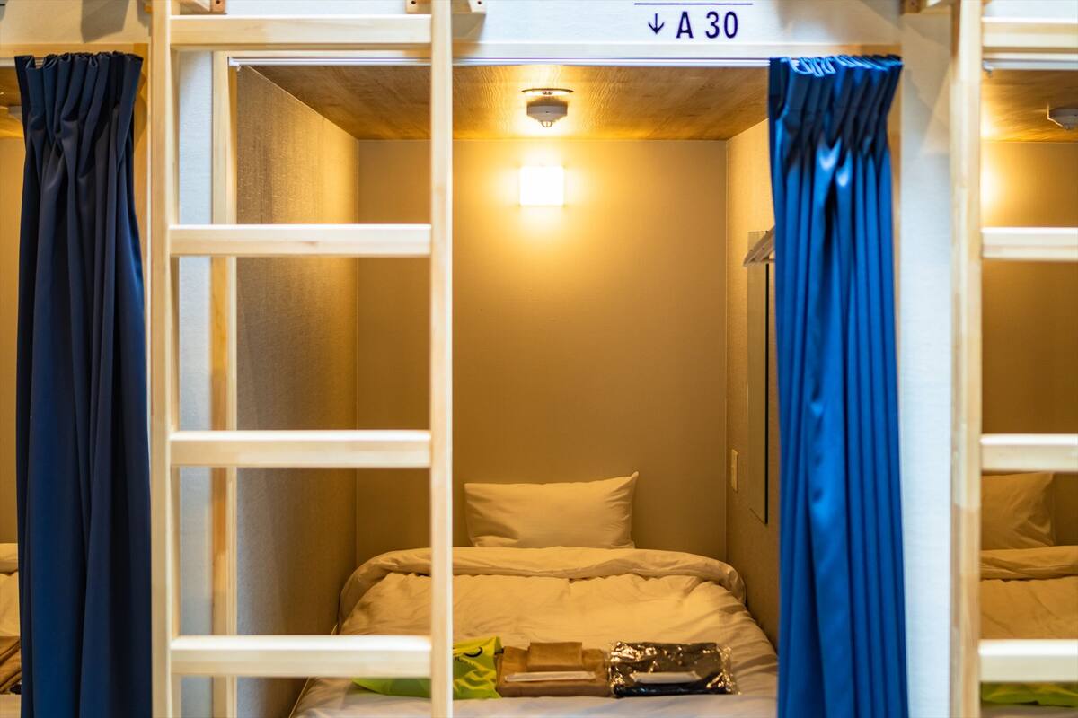 Pequeña habitación privada con literas, una cama individual, una lámpara y un cartel que indica el número de habitación A30.