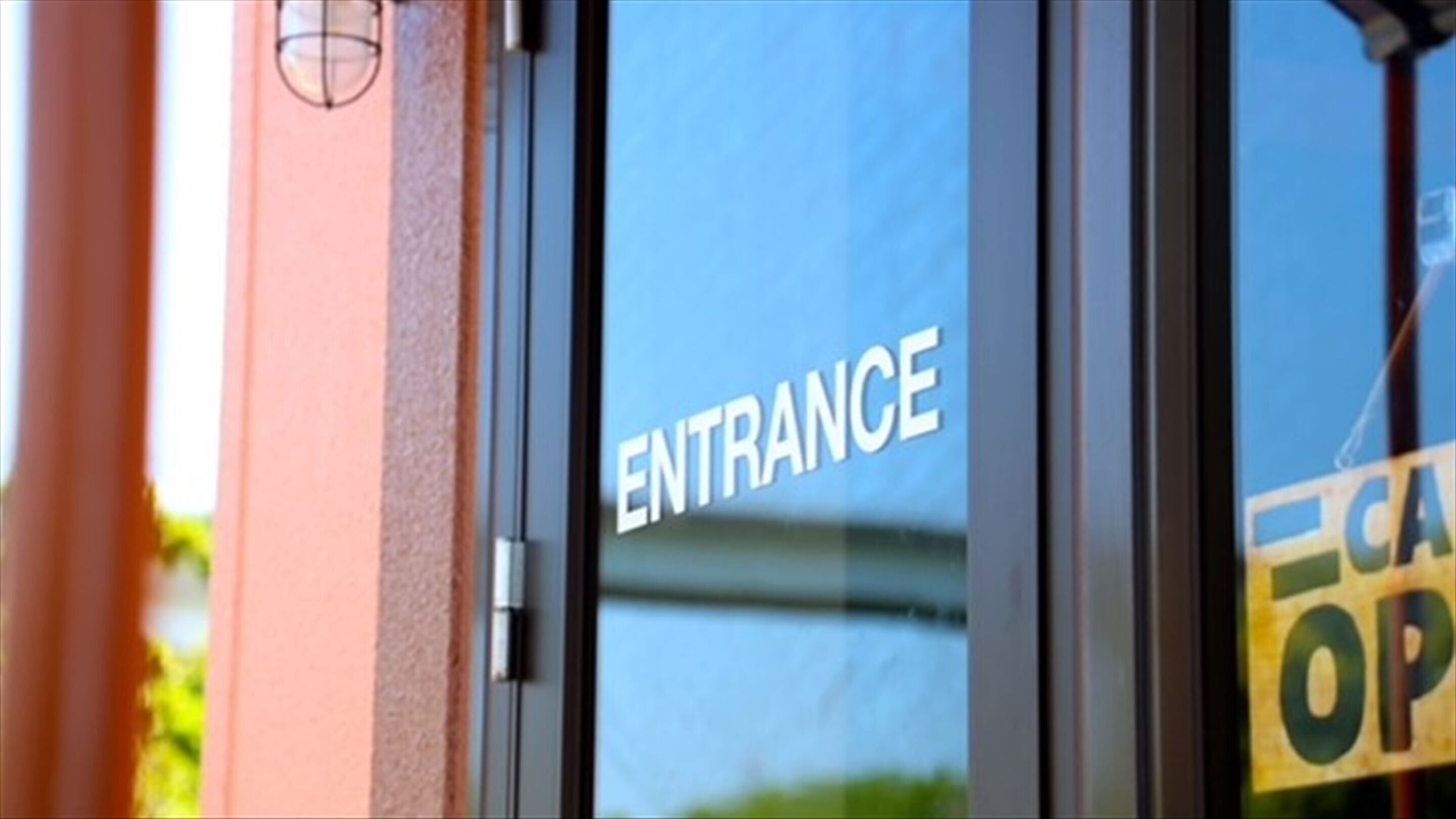 Een heldere glazen deur, waarop het woord 'ENTRANCE' staat.