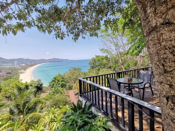 A balcony with a table and chairs overlooking a beach and ocean. - On The Hill Karon Resort (Karon)