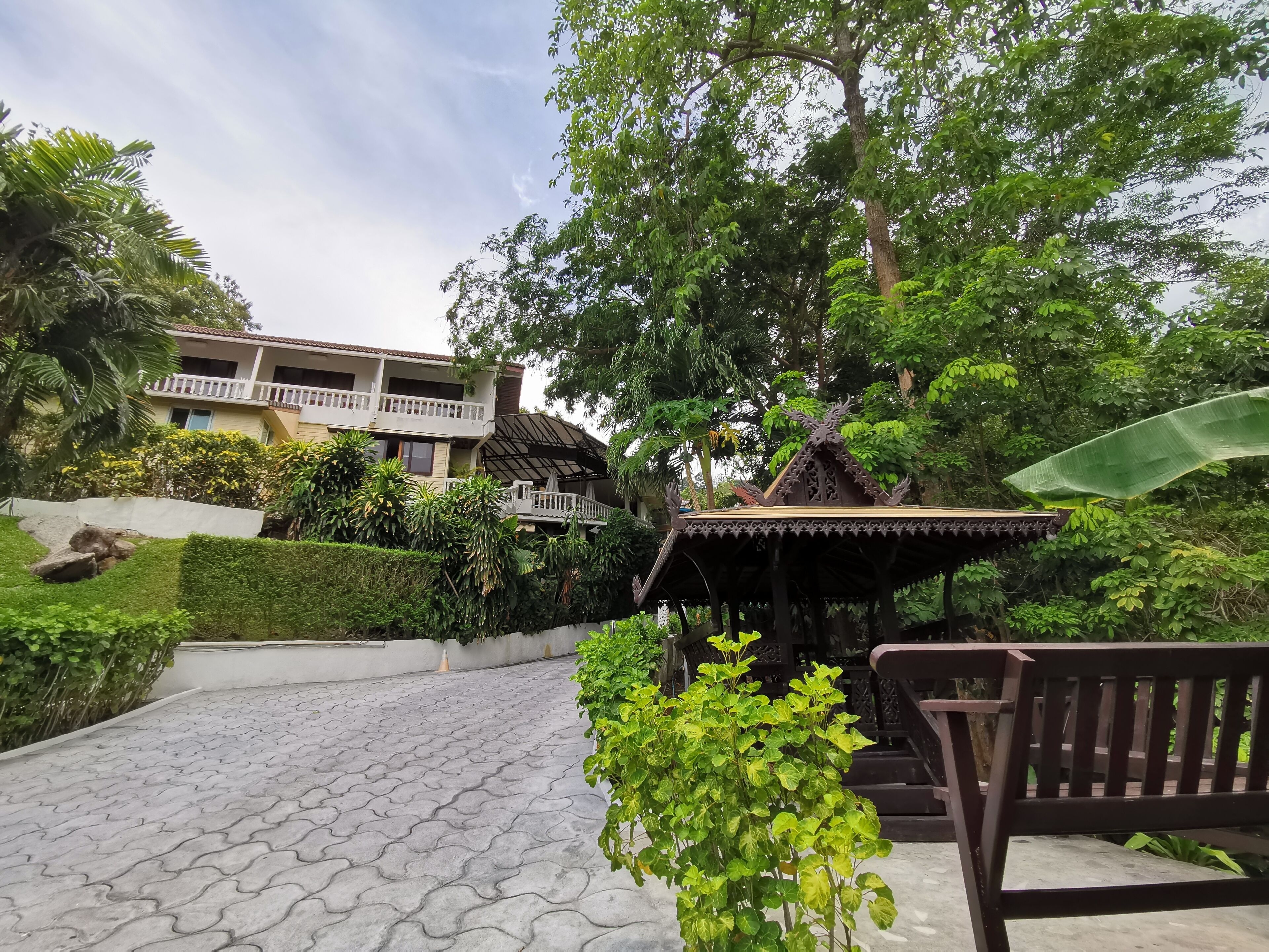 A courtyard with a gazebo, a bench, and a building with a balcony.