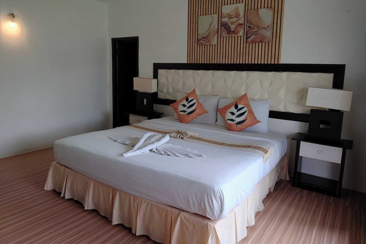 A hotel room with a large bed, two bedside tables, a headboard, and a wall with artwork.
