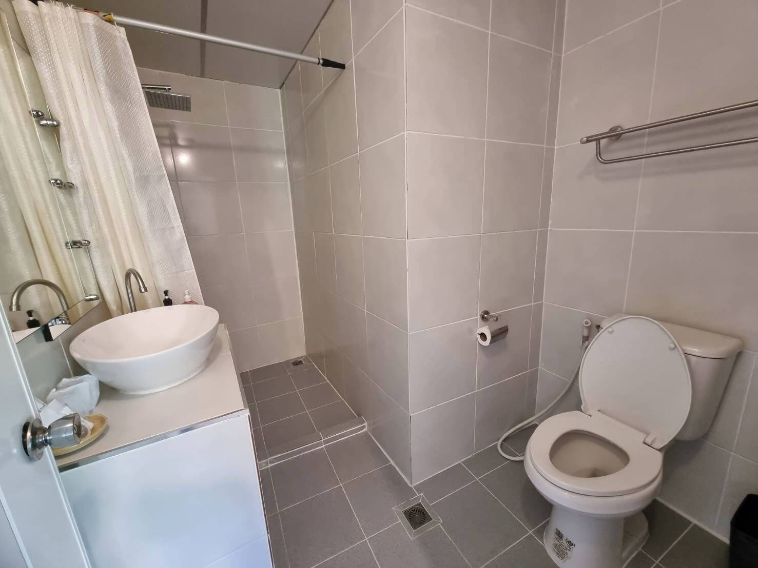 A bathroom with a white sink, a toilet, and a shower area.