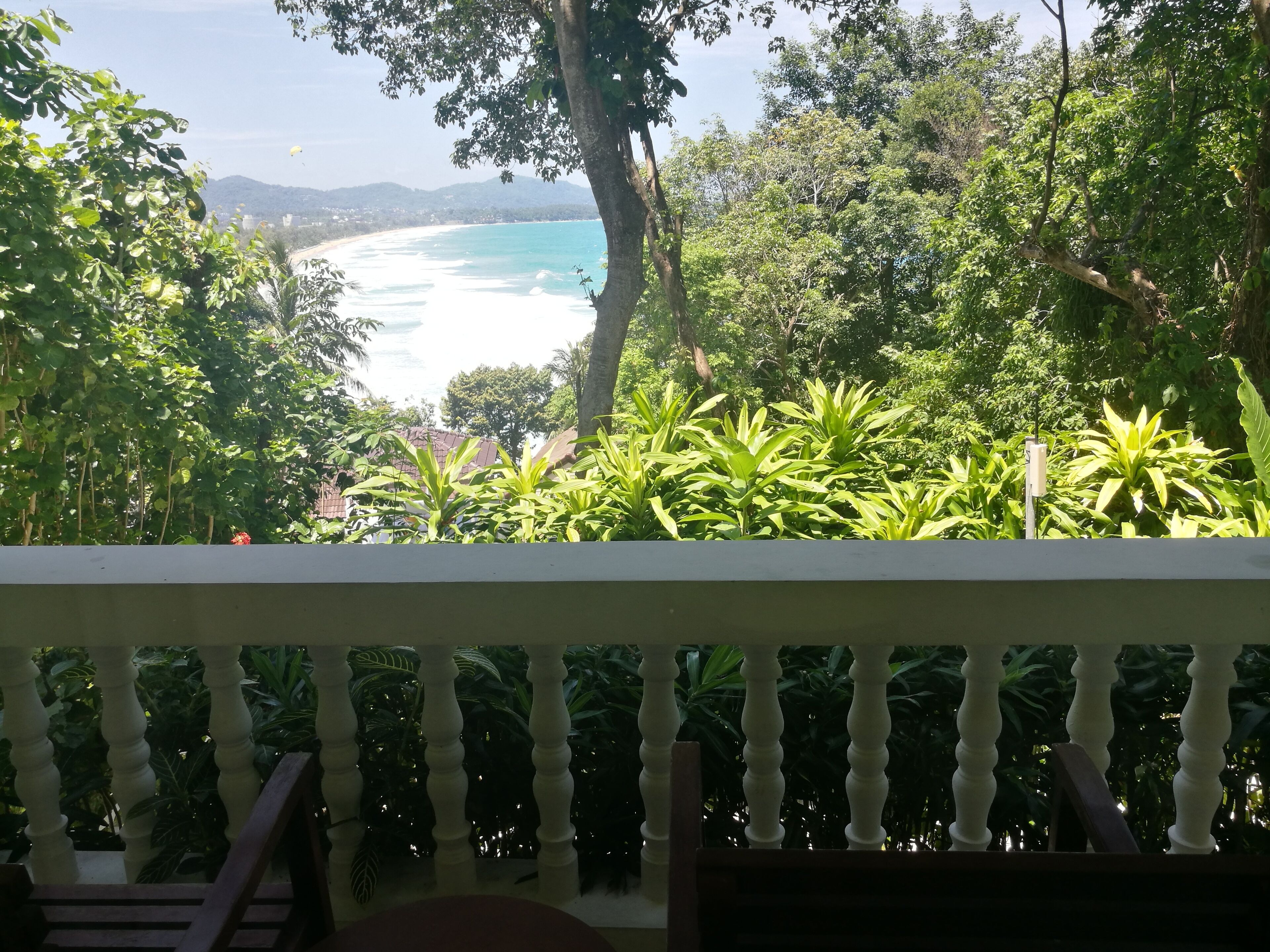 Un balcone con vista sulla spiaggia e vegetazione lussureggiante.