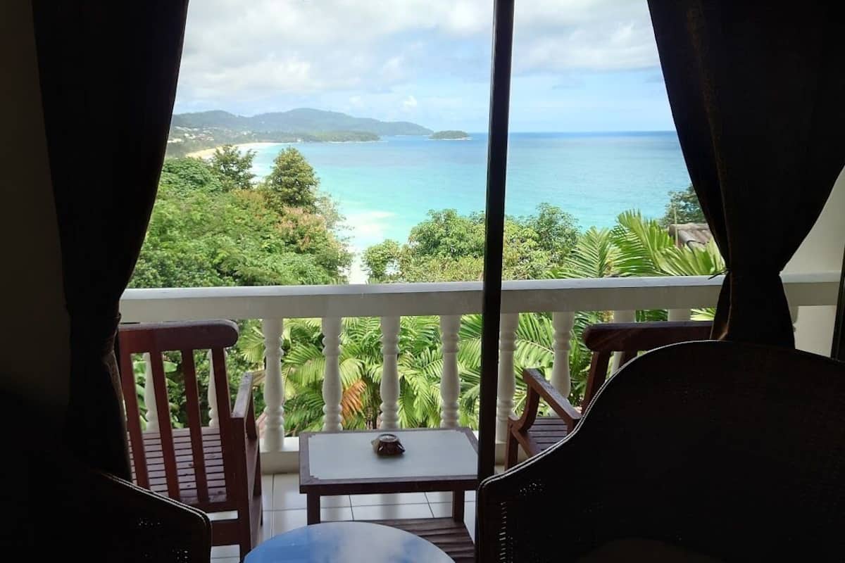 A balcony with a view of the ocean and greenery.