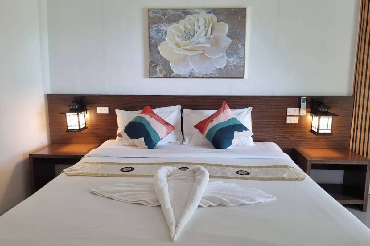 A hotel room with a large bed, two nightstands, two wall-mounted lamps, and a painting of a flower on the wall.