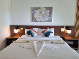 A hotel room with a large bed, two nightstands, two wall-mounted lamps, and a painting of a flower on the wall.