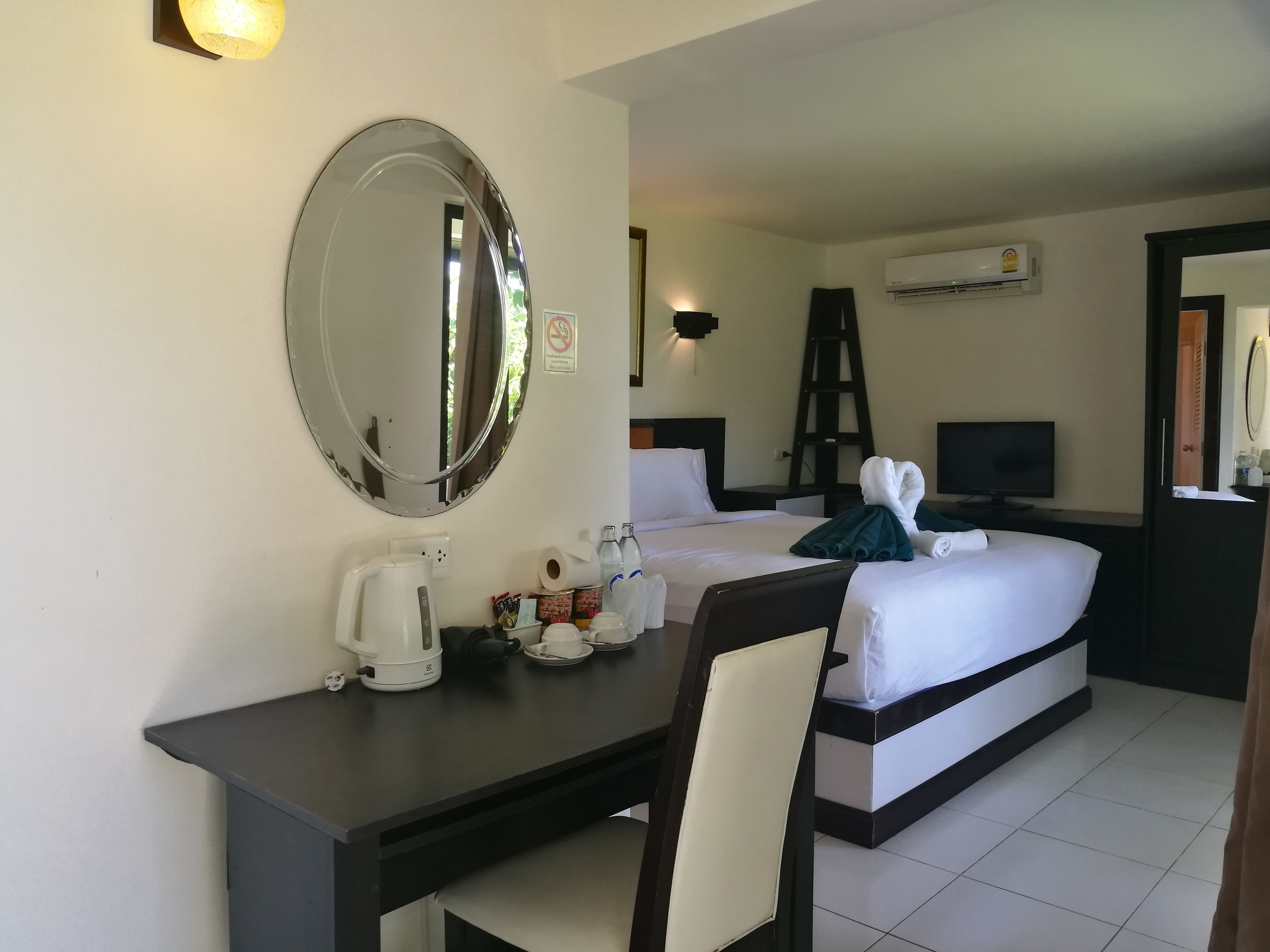 Une chambre d’hôtel équipée d’un lit, d’un bureau avec une machine à café, d’une télévision et d’un miroir.