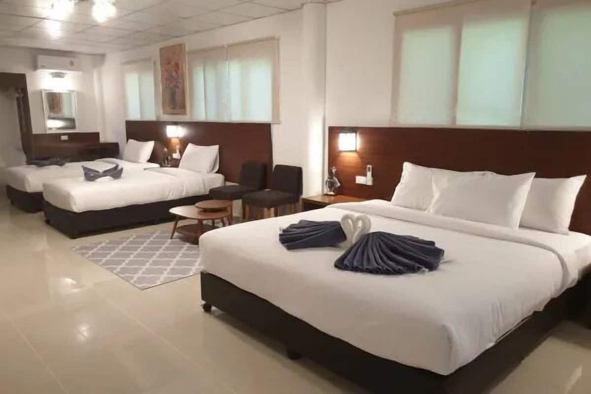A hotel room with two beds, a small table, and a chair.