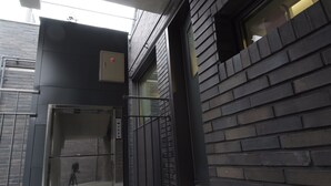 An elevator with a glass door, a fire alarm, and a metal railing. - DW Stay Hongdae (Seoul)