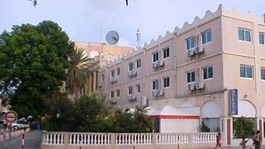 Un edificio de varios pisos con balcones, una antena parabólica y una señal de prohibido estacionar.