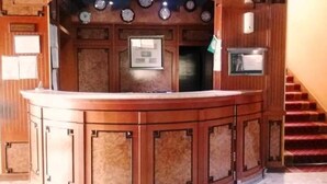 Un mostrador de recepción curvo con terminación de madera y un reloj integrado.