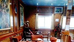 Un vestíbulo con paneles de madera, piso de mármol y una mezcla de muebles de madera y tapizados.