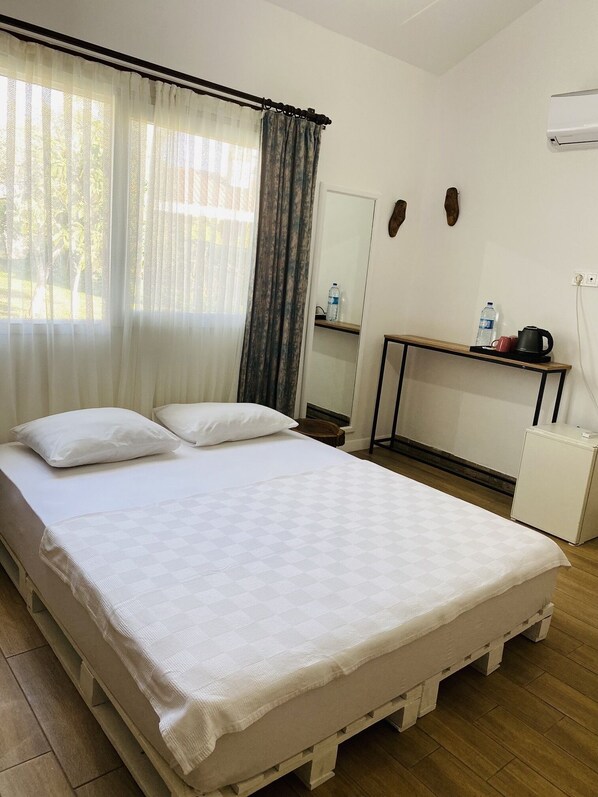 A neatly arranged hotel room with a bed, a small desk, a mirror, and a window with curtains. - Çıralı Marina Loft Hotel (Kemer)